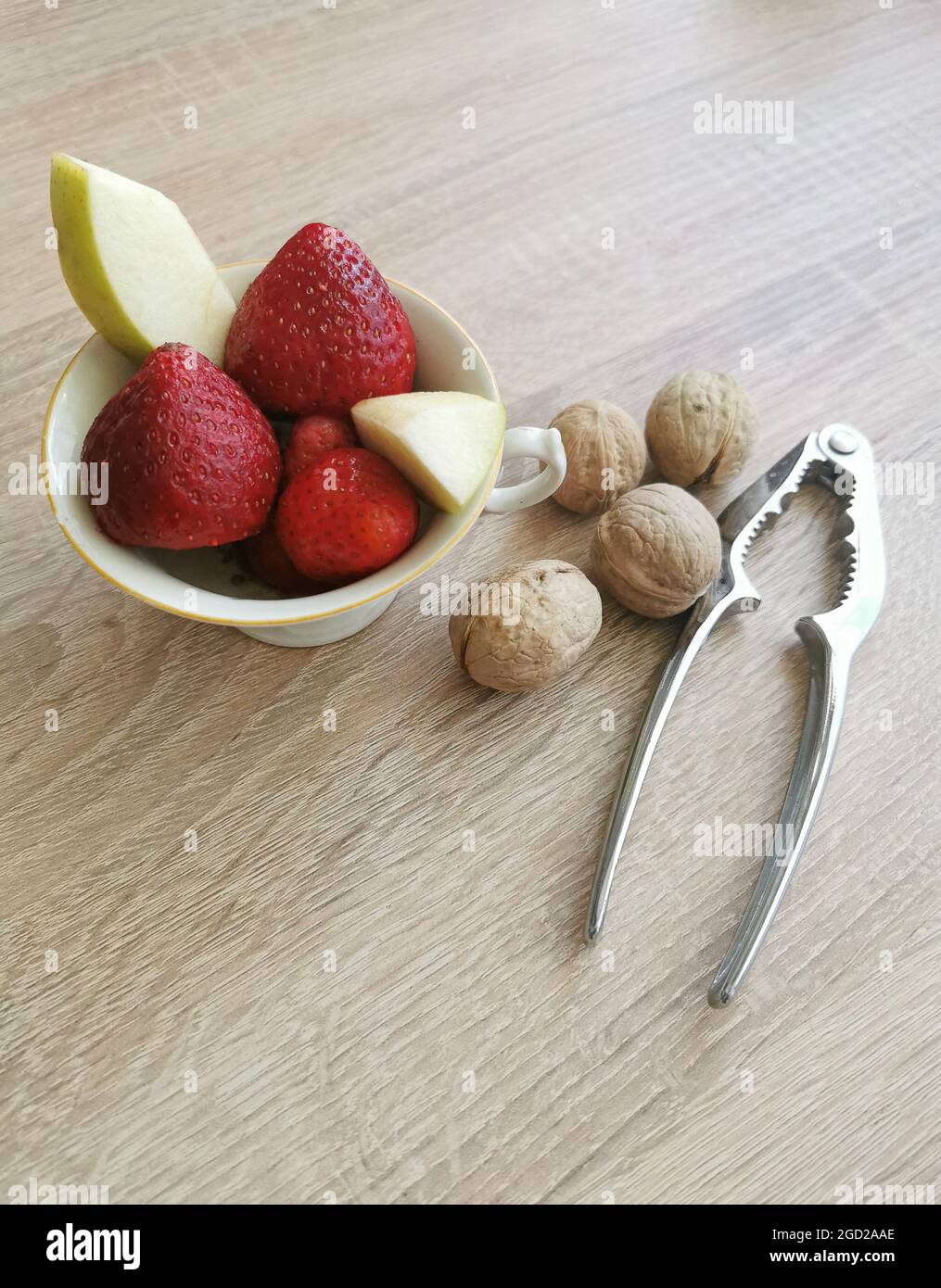 Fresh strawberries, apple pieces, walnuts and a nutcracker Stock Photo