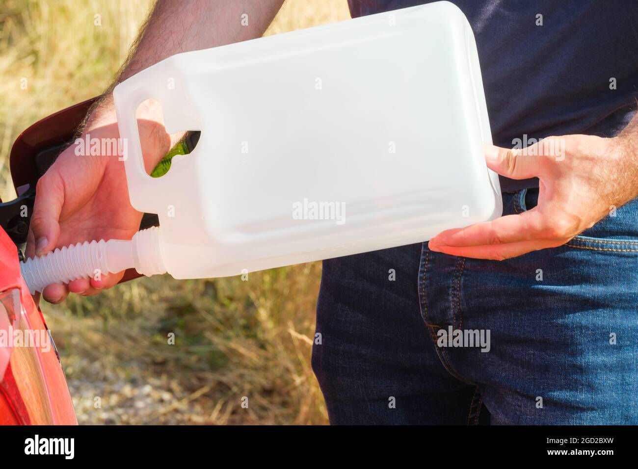 Man filling up fuel or diesel into the gas tank from canister in the field.  Stock Photo
