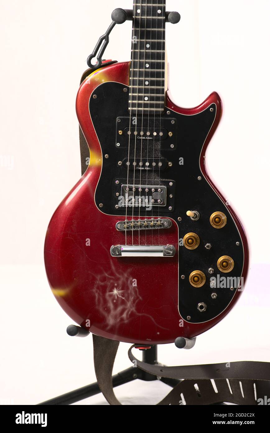 Dark red electric guitar on a stand isolated on a white background