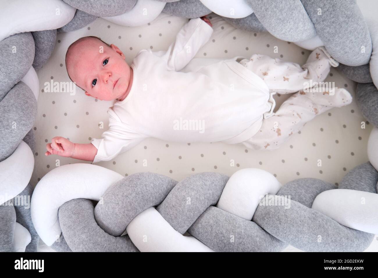 Portrait of a baby boy aged one month lying with his eyes open in 