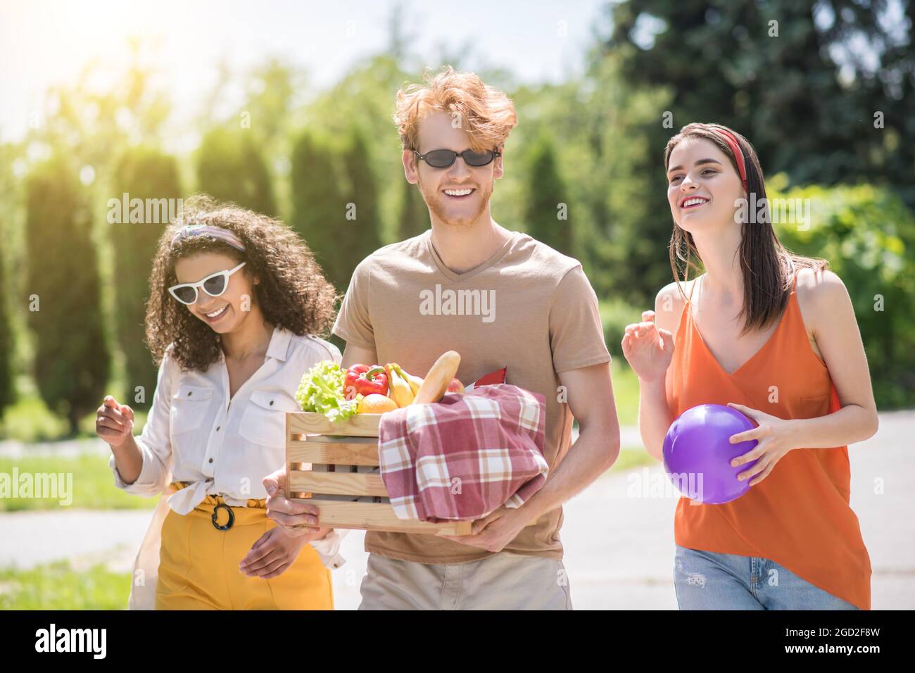 Three young happy friends going on picnic Stock Photo