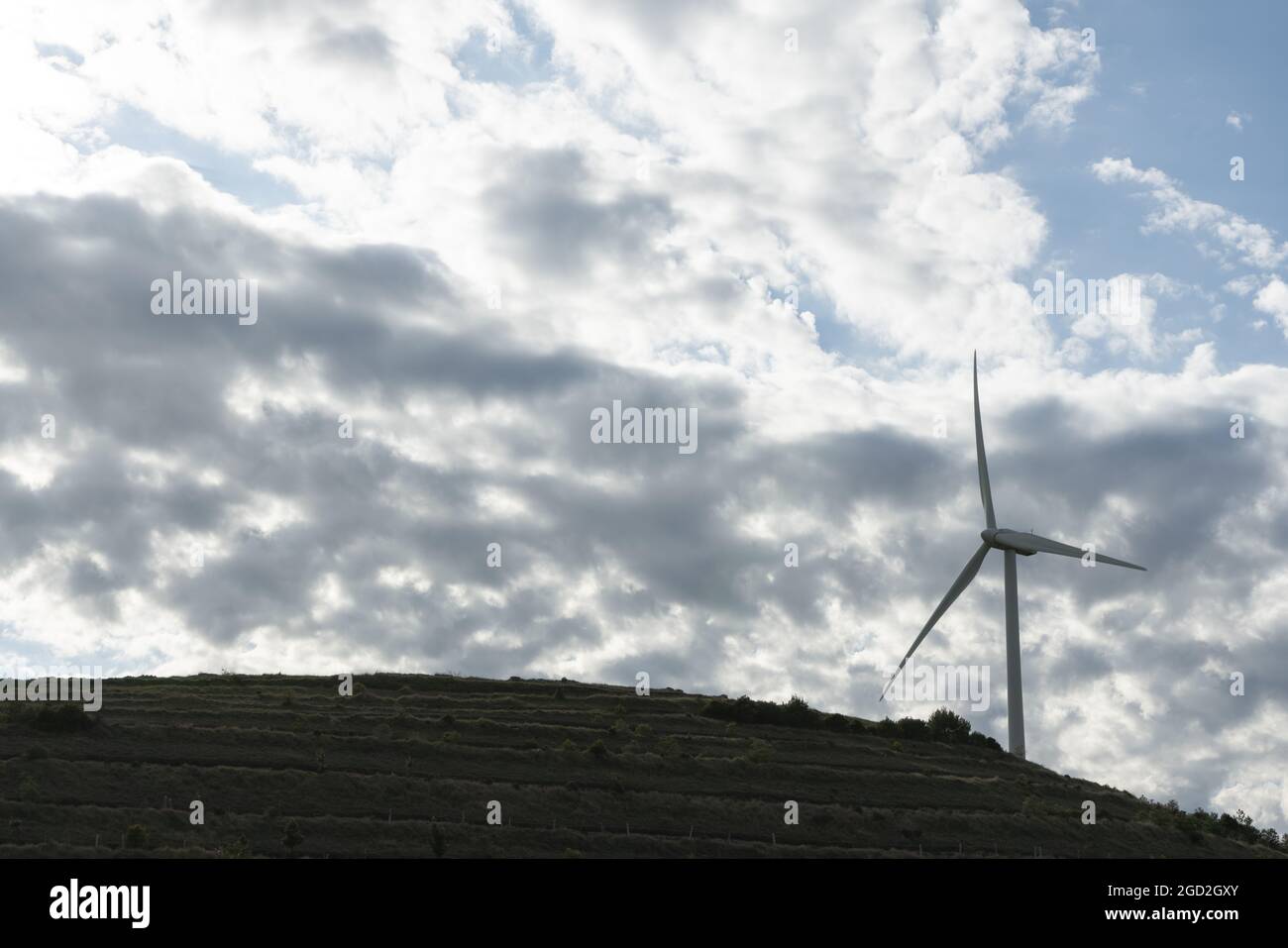 Low angle shot of a wind turbine on top of a hill captured on a cloudy ...