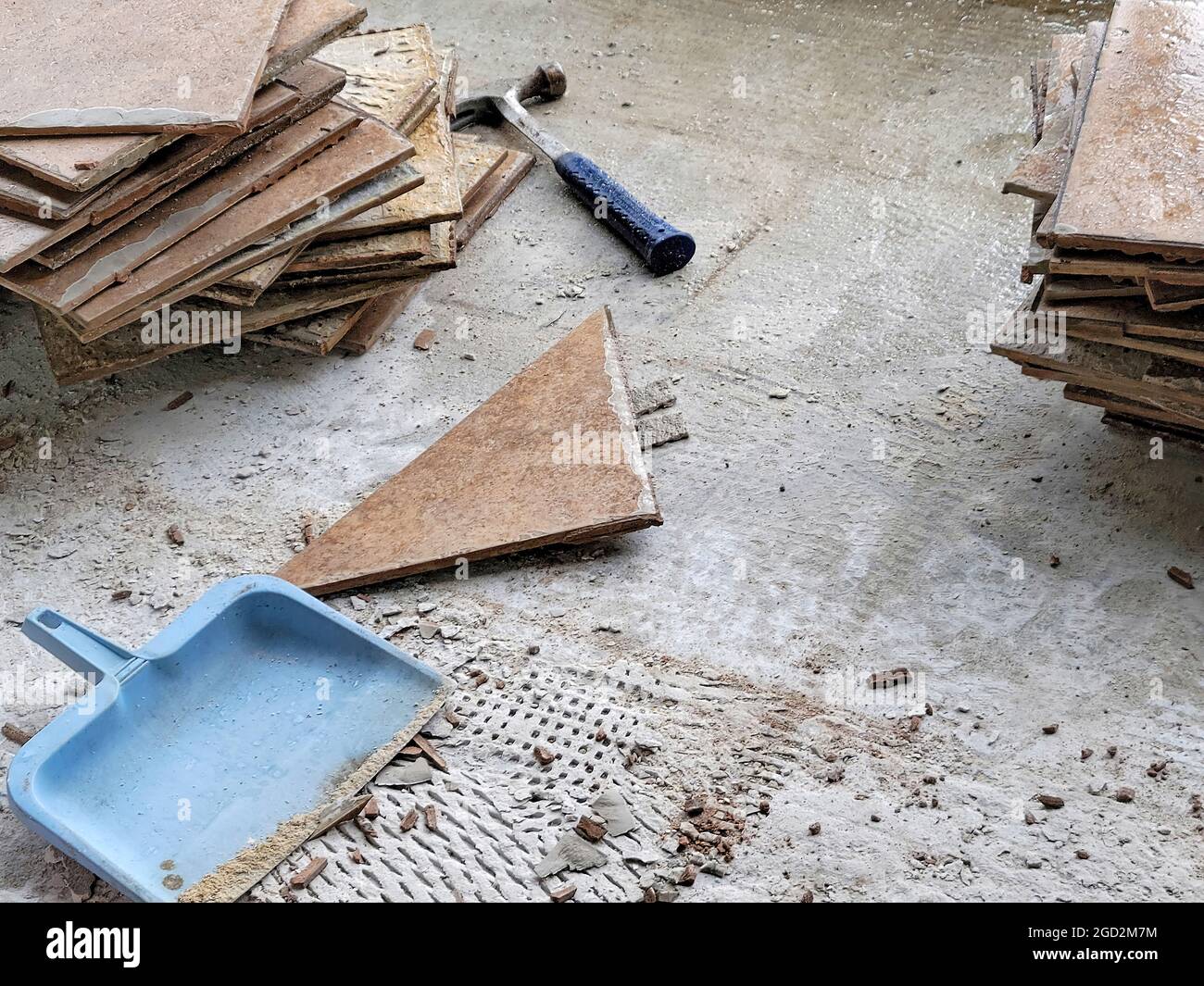 blue dustpan with a hammer and broken ceramic floor tile Stock Photo