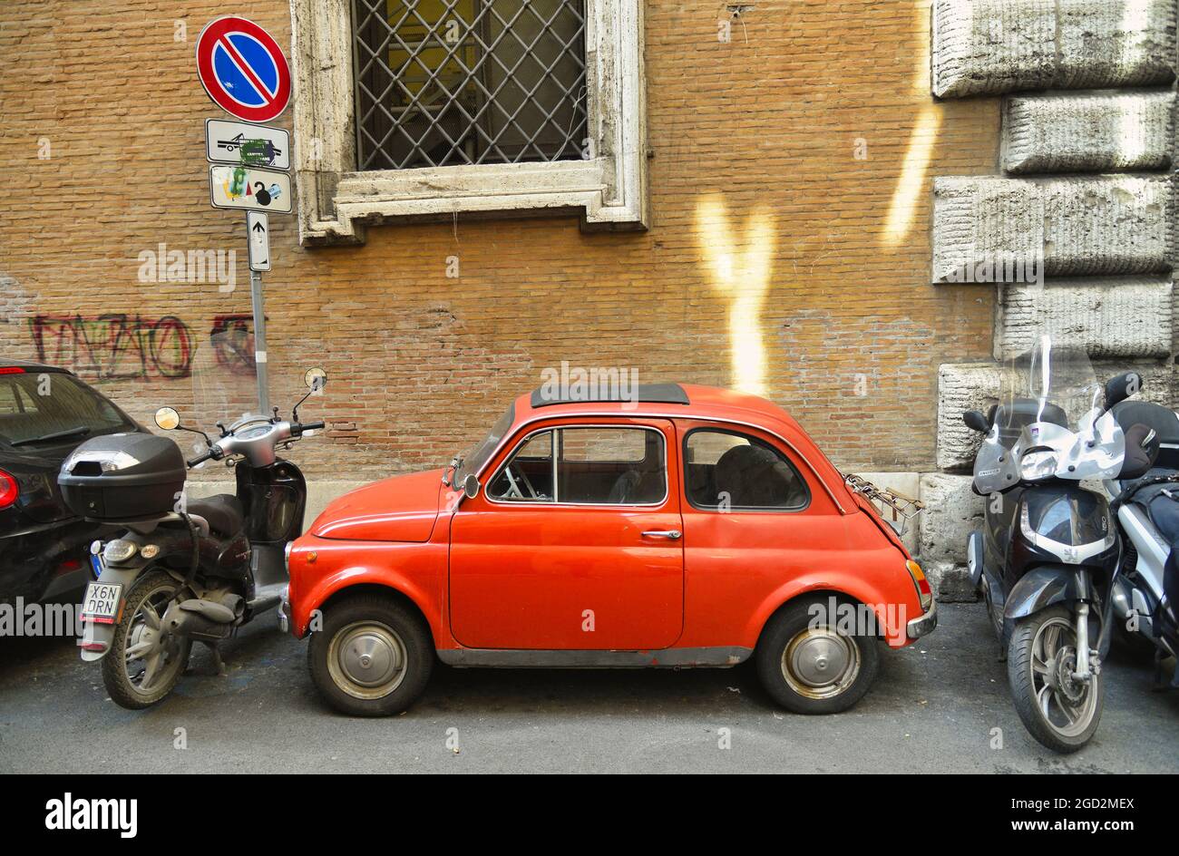 Side view of an old red Fiat 500 parked in a narrow street in Rome, Italy Stock Photo