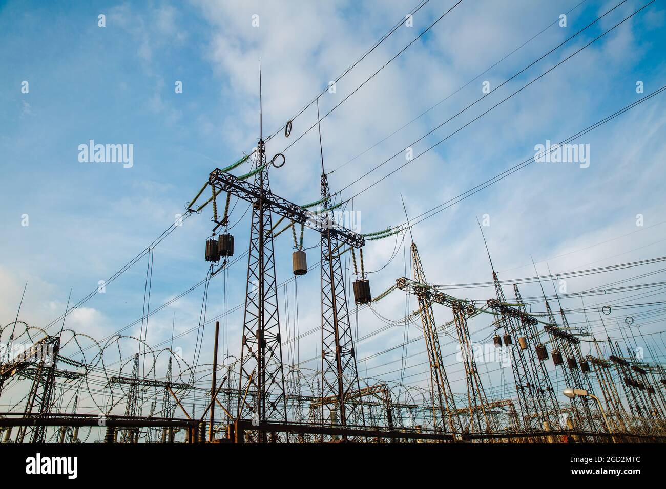 Electrical pylons and high voltage power lines are behind a barbed wire fence. Stock Photo