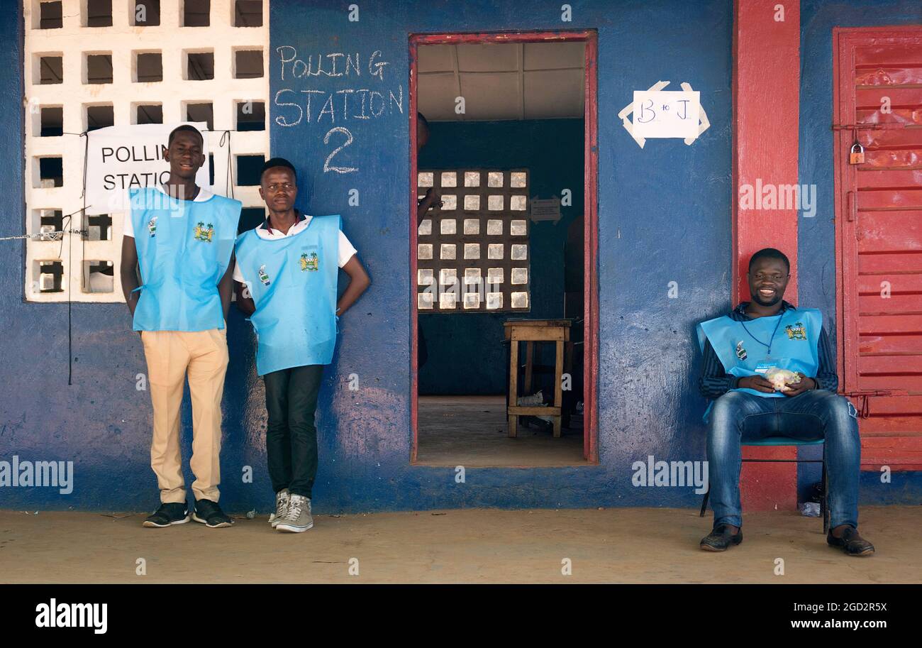 Three poll workers stand outside a polling station in Sierra Leone which marked a peaceful transfer of power from a ruling party to the opposition when Julius Maada Bio of the Sierra Leone People's Party assumed the presidency followinga run-off election held on March 31, 2018. Stock Photo