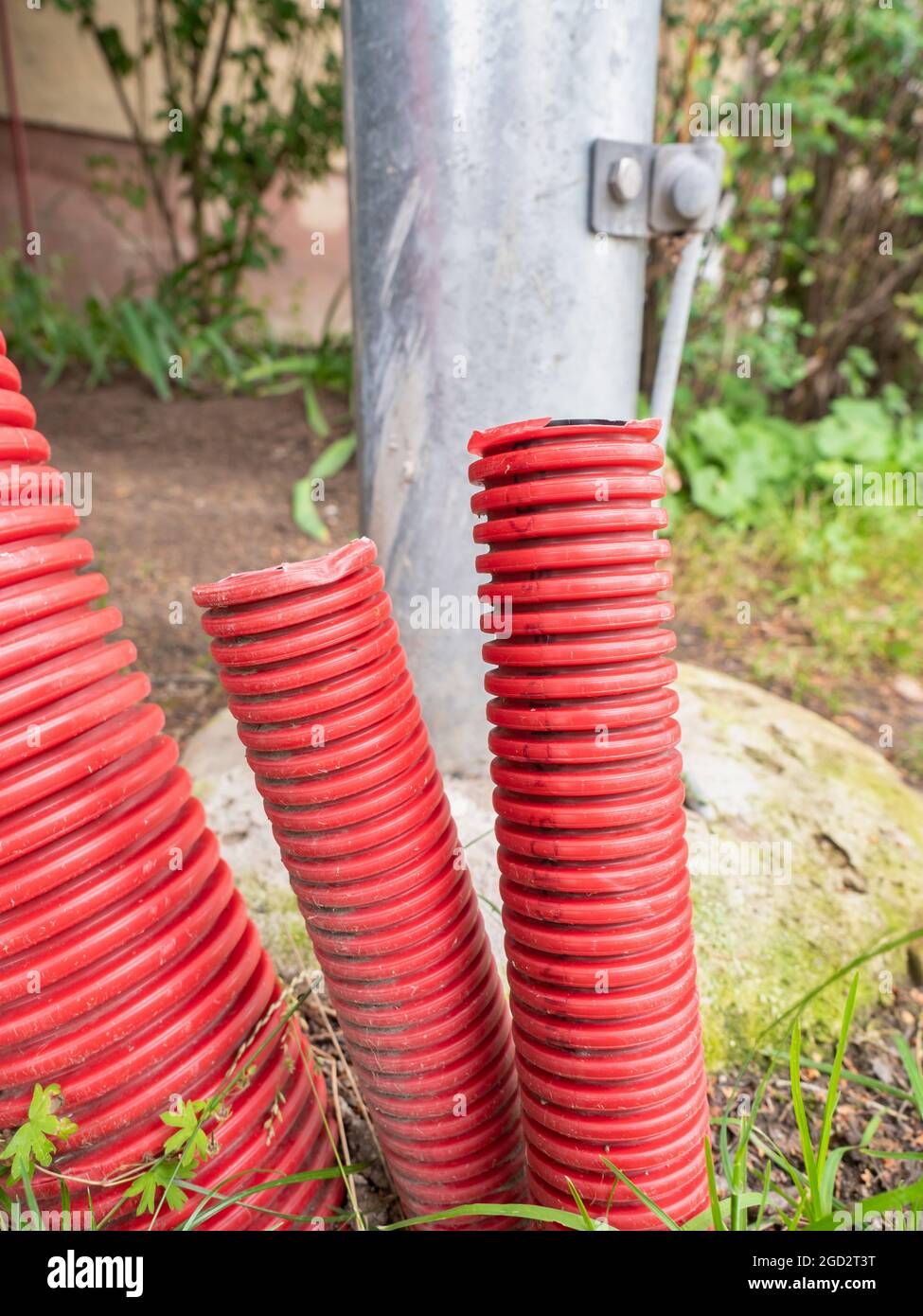 Ribbed red plastic pipes at electric pole. Safety pipes ready for