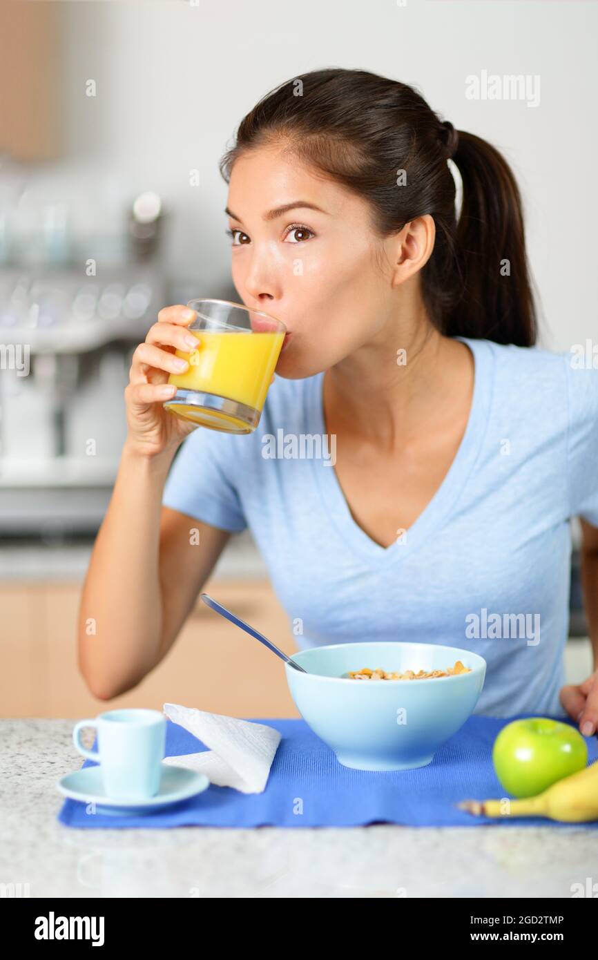 Breakfast at home Asian woman drinking fresh cold pressed orange juice