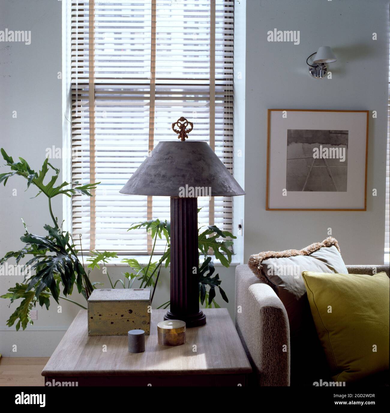 Closeup of designer livingroom in NYC with side table and lamp against wooden venetian blind. Stock Photo