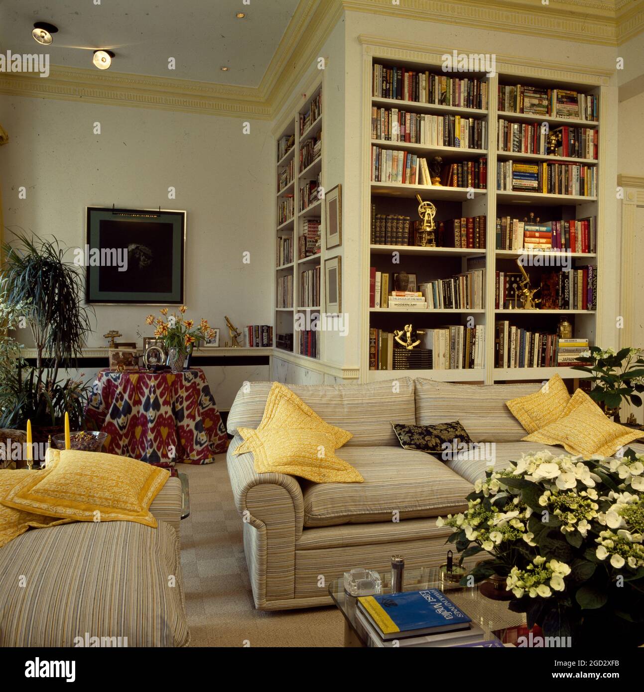 Floor to ceiling shelving unit on l-shaped designer livingroom in NYC eighties Stock Photo