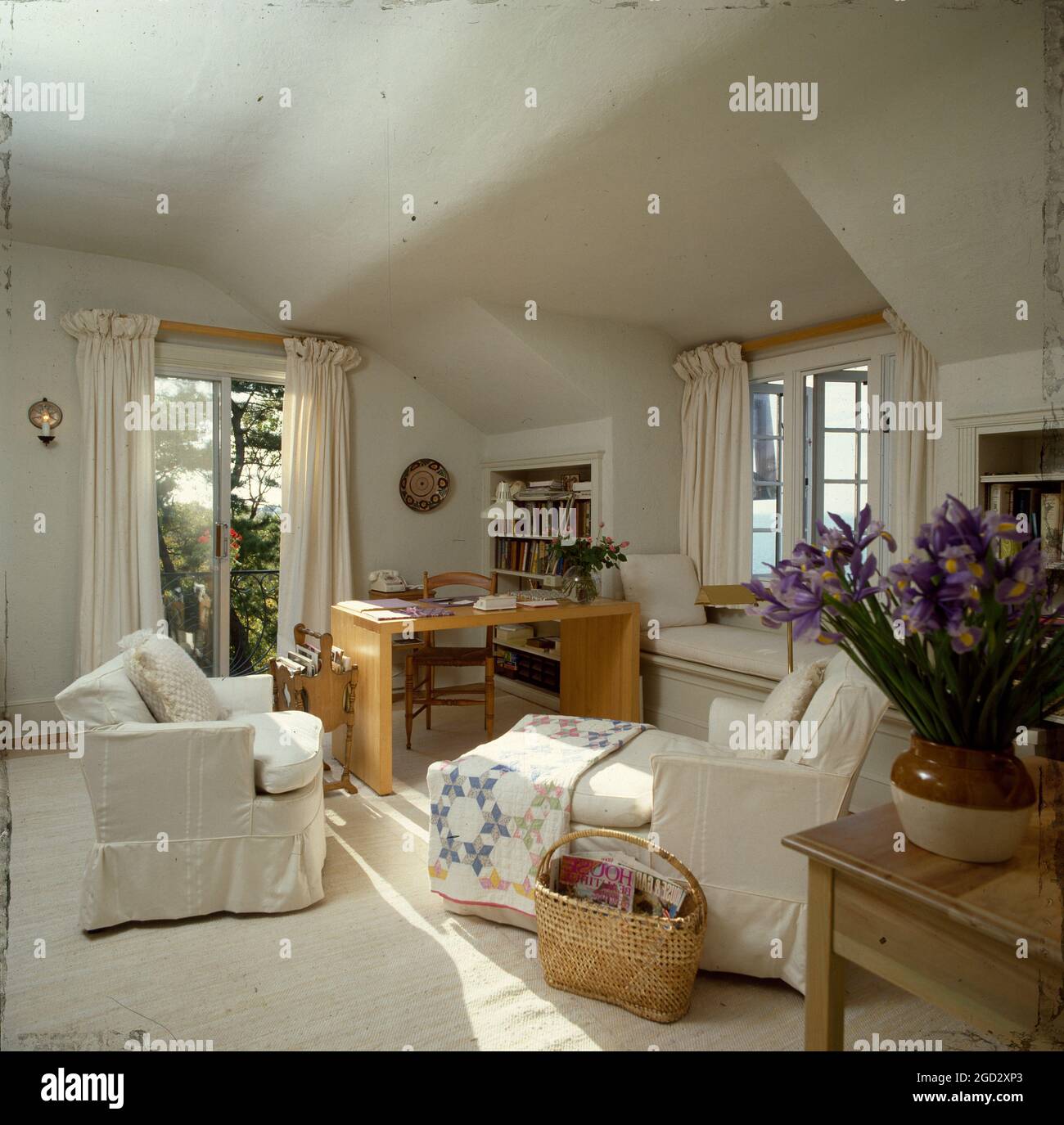 Cream painted and furnished attic sittingroom with french window to outside balcony. Stock Photo