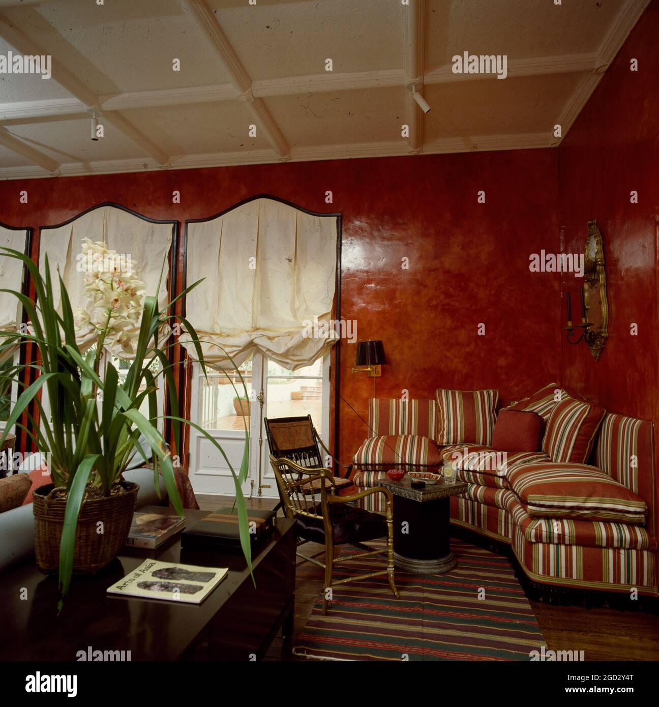 Designer livingroom in NYC eighties with lacquered wall finish and striped fabric on sofas Stock