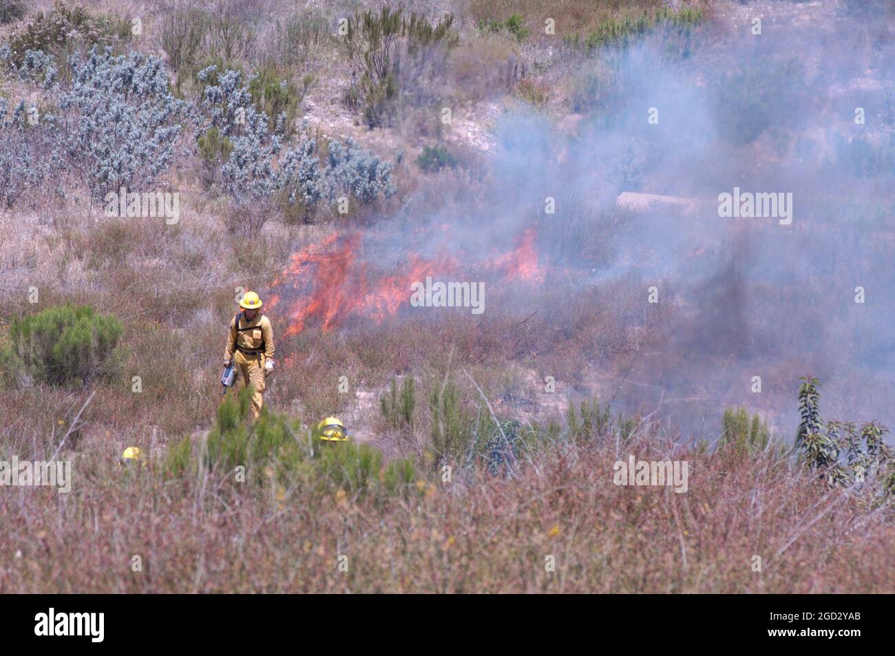 Firefighters near flames on controlled brush burn aboard MCAS Miramar Stock Photo