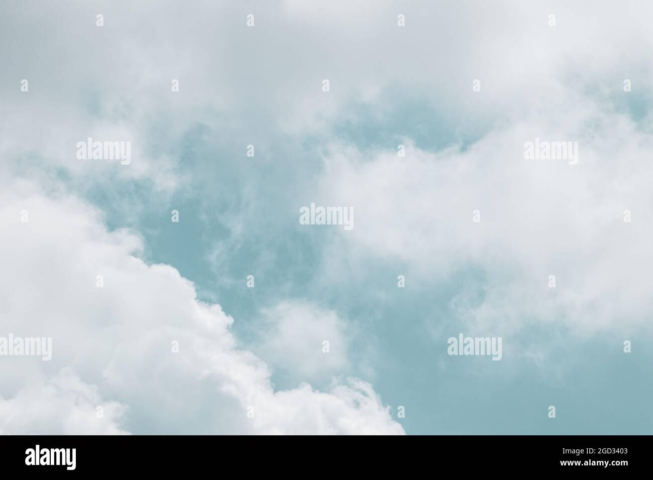 Fluffy white high clouds framing bright blue color graded sky, cloudscape background. Skyscape natural heavenly scenery Stock Photo