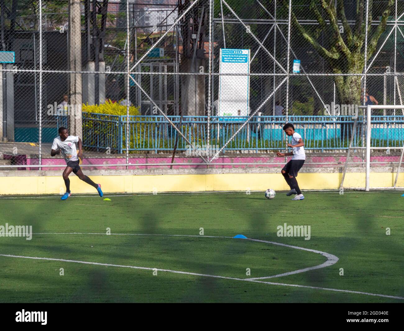 Medellin, Colombia - July 30 2021: Two Young Latin Teenagers in Sportswear Training Soccer with Several Balls on a Sunny Day Stock Photo