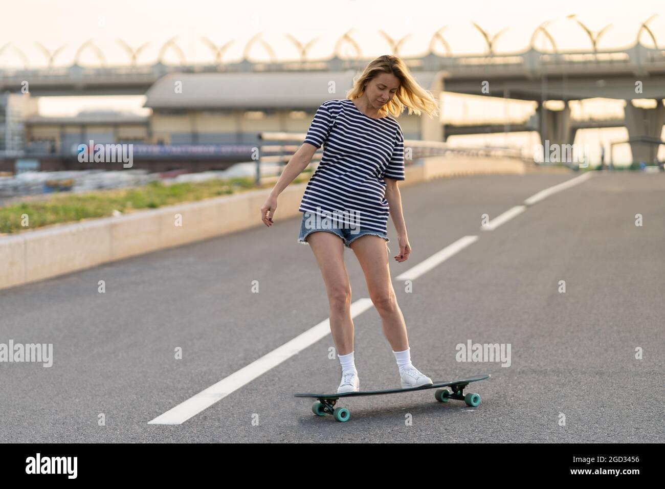 Active adult woman longboarder riding longboard on empty road. Female relax  on skateboard after work Stock Photo - Alamy