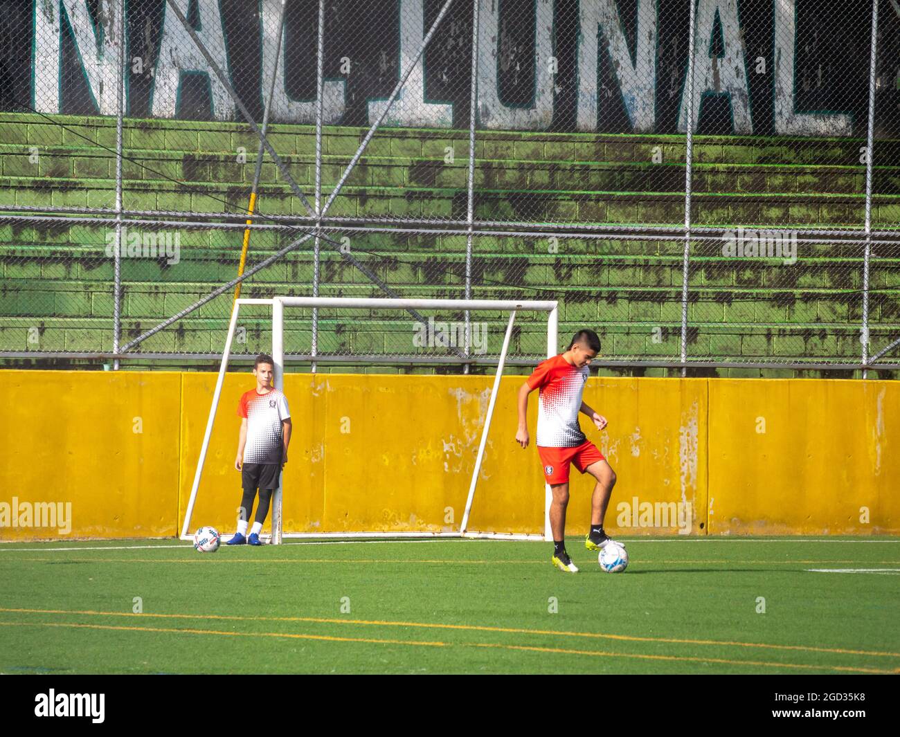 Medellin, Colombia - July 30 2021: Two Young Latin Teenagers in Sportswear Training Soccer with Several Balls on a Sunny Day Stock Photo