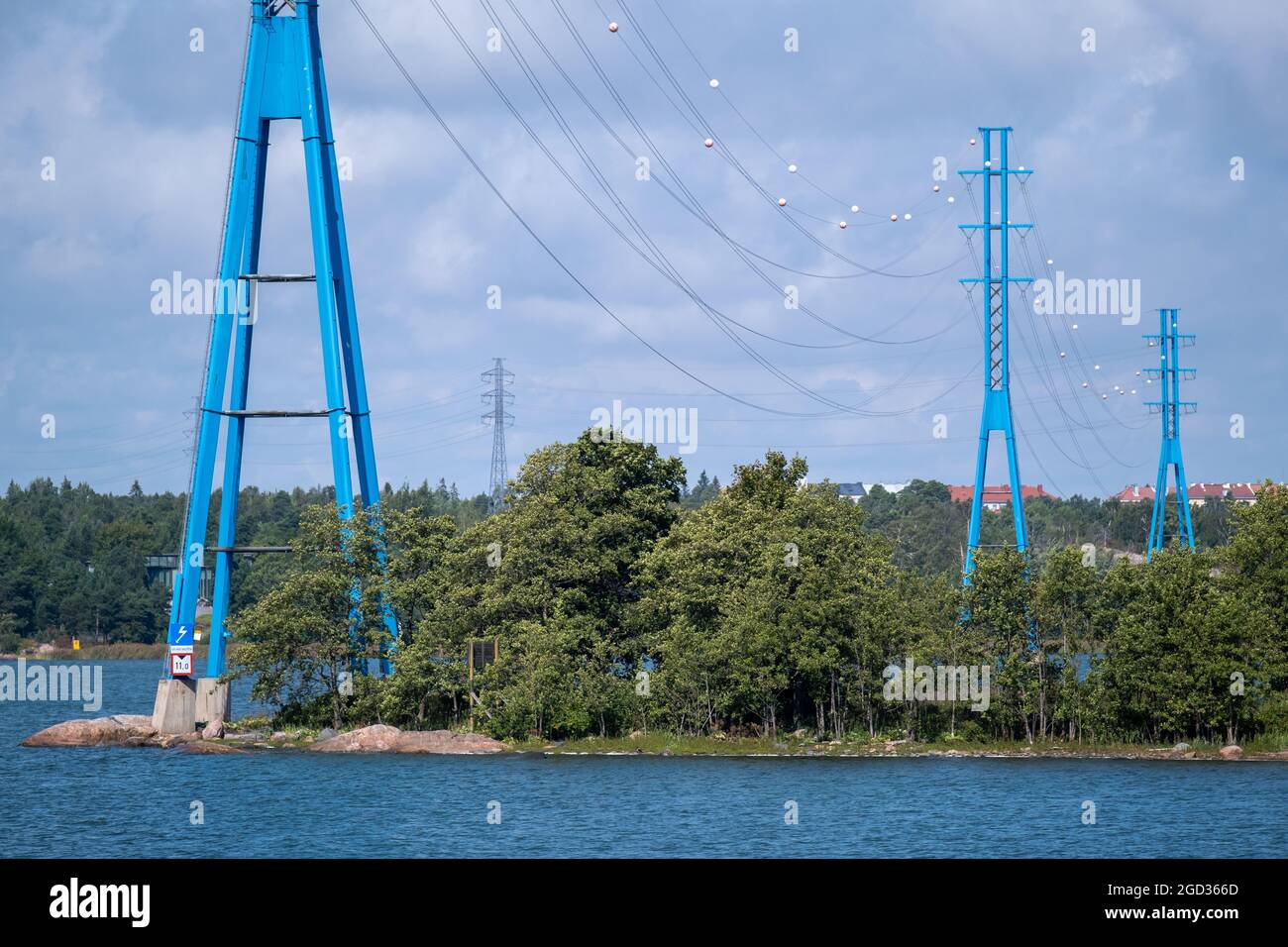 Helsinki / Finland - AUGUST 10, 2021: A line of modern high voltage electricity pylons on the shore against cloudy sky. Stock Photo