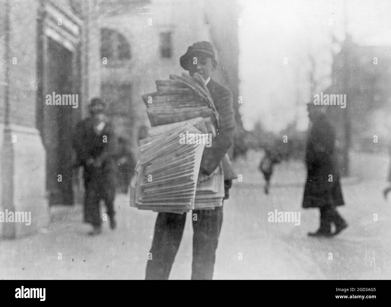 Newsboy on a city street ca. between 1909 and 1920 Stock Photo