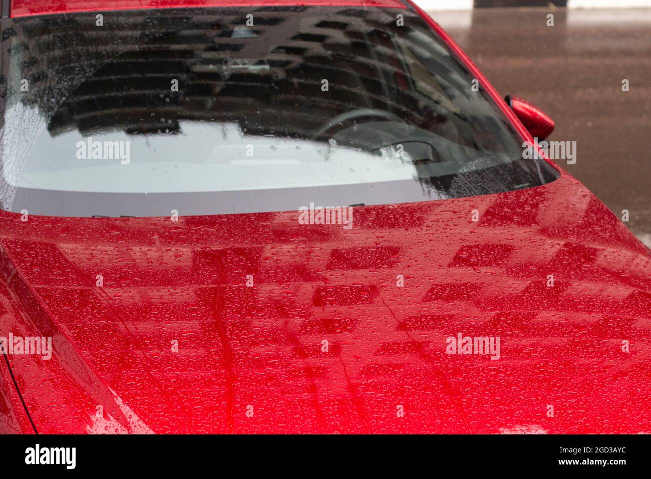 Red car in the parking lot. Car surface. Wet car after rain. Details of