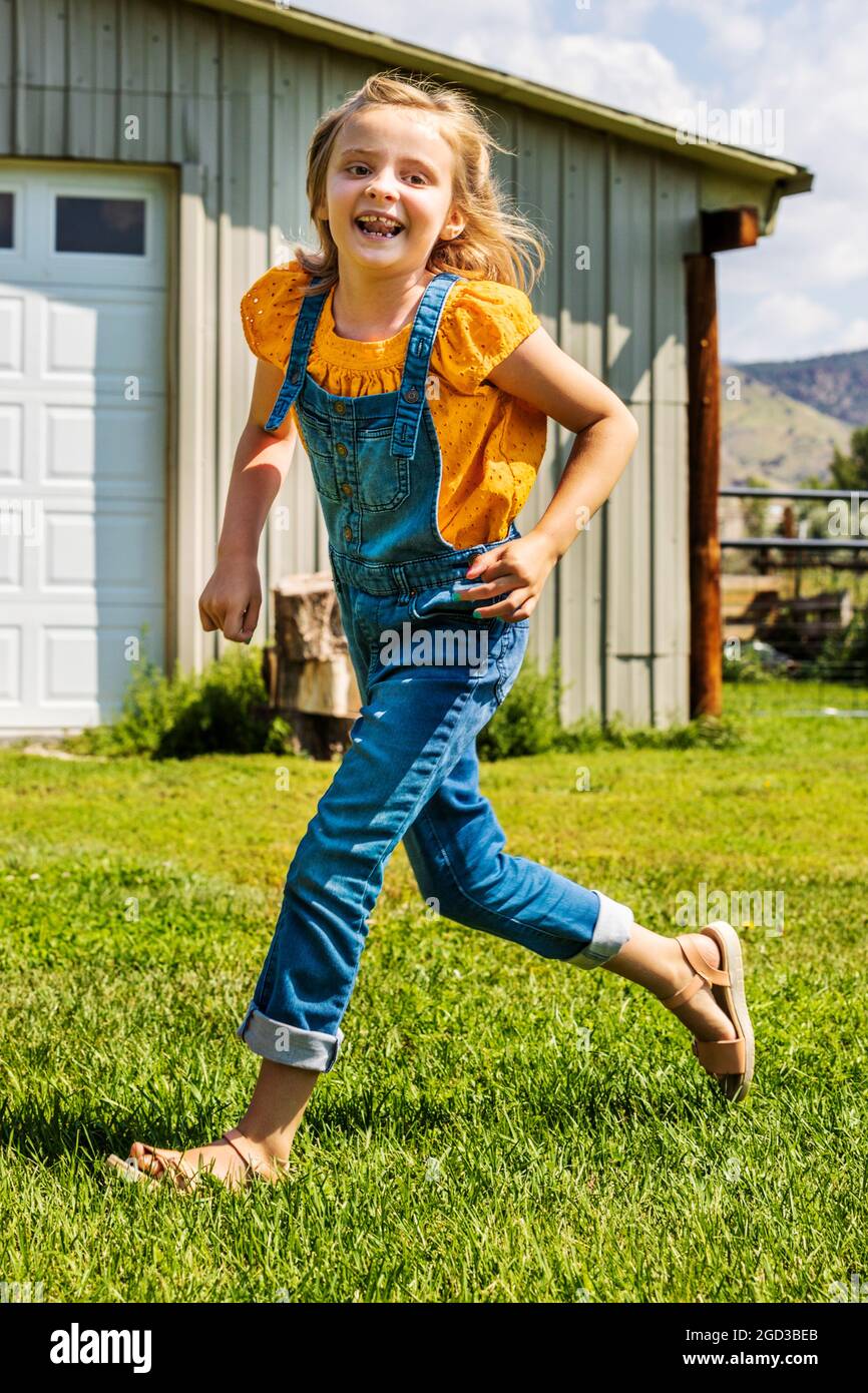 Young girl playing & running in grassy yard Stock Photo