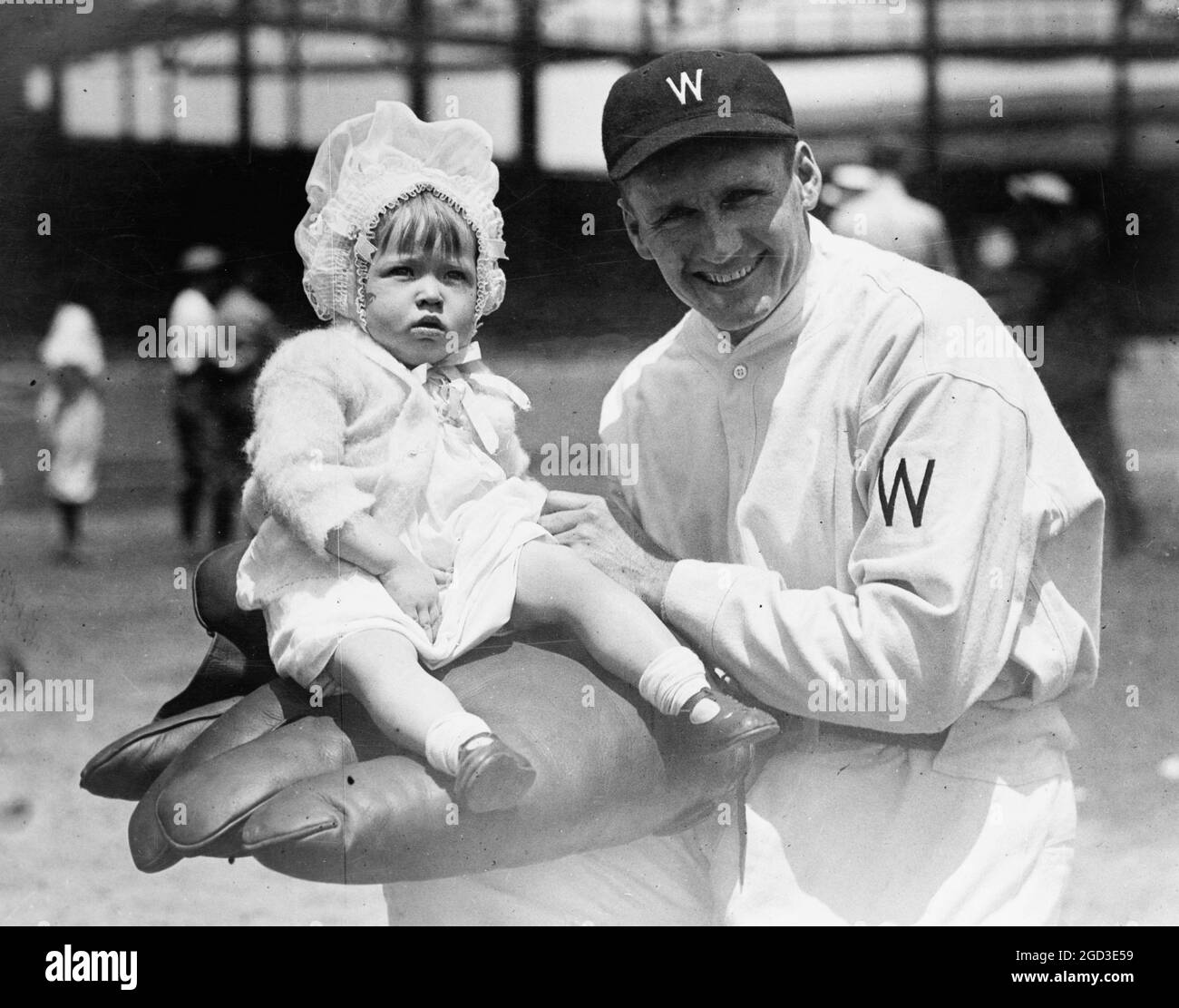 Walter Johnson, half-length portrait, facing slightly left, holding little girl on large glove ca. [between 1909 and 1932] Stock Photo