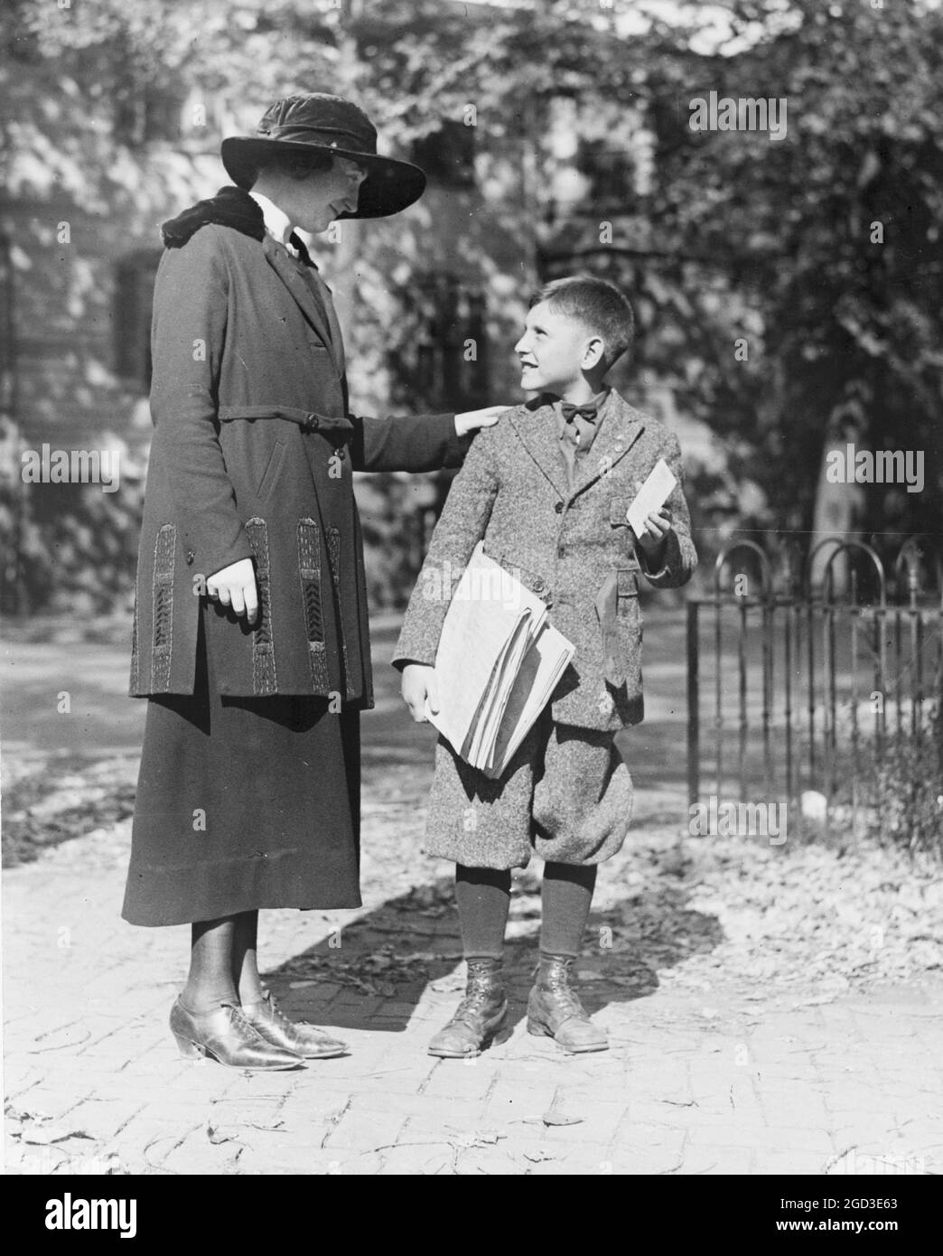 A policewoman in training, speaking to a young man, possibly a newsboy ca. 1909 Stock Photo