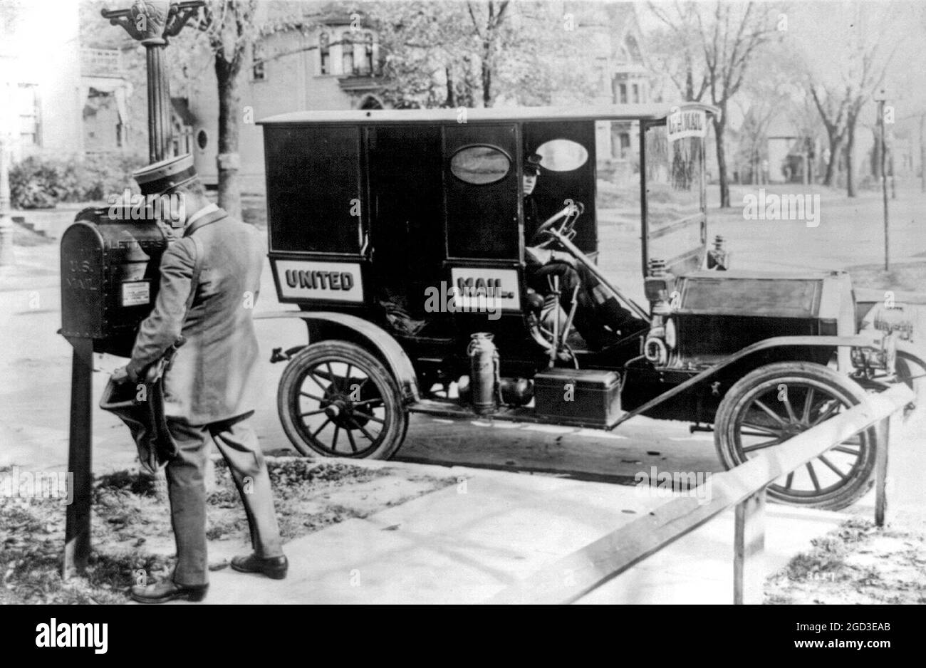 U.S. mailman emptying mailbox & mail truck ca. between 1909 and 1940 Stock Photo