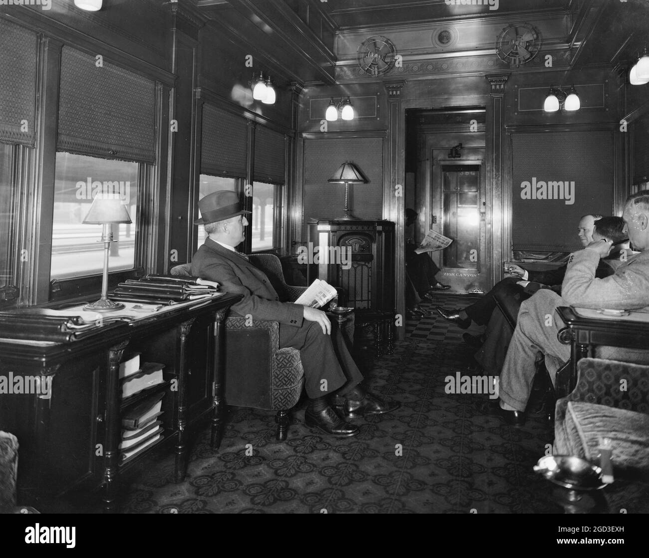 Men speaking, sitting in a train car ca. between 1910 and 1935 Stock Photo