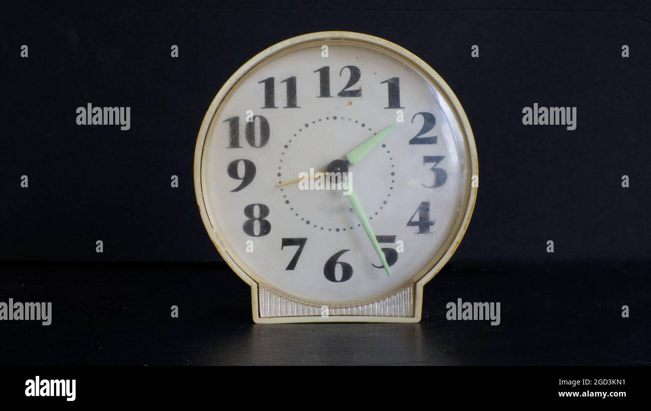 An Old Alarm Clock Against a Black Background Stock Photo