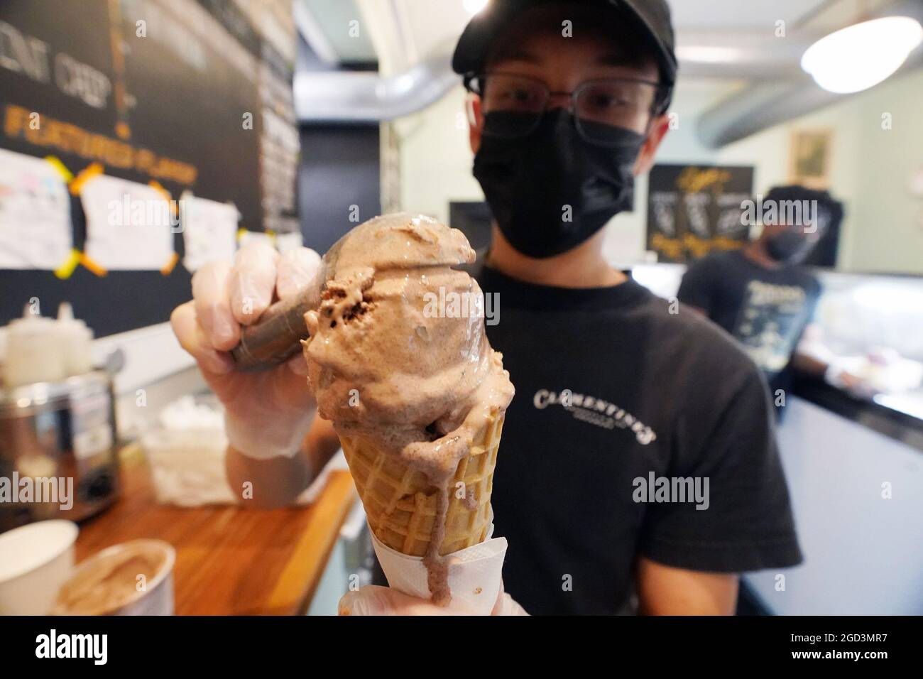 St. Louis, United States. 10th Aug, 2021. Clerk Joe Kelley scoops up  Missouri Mud ice cream on to a cone at Clementines Creamery in St. Louis on  Tuesday, August 10, 2021. The