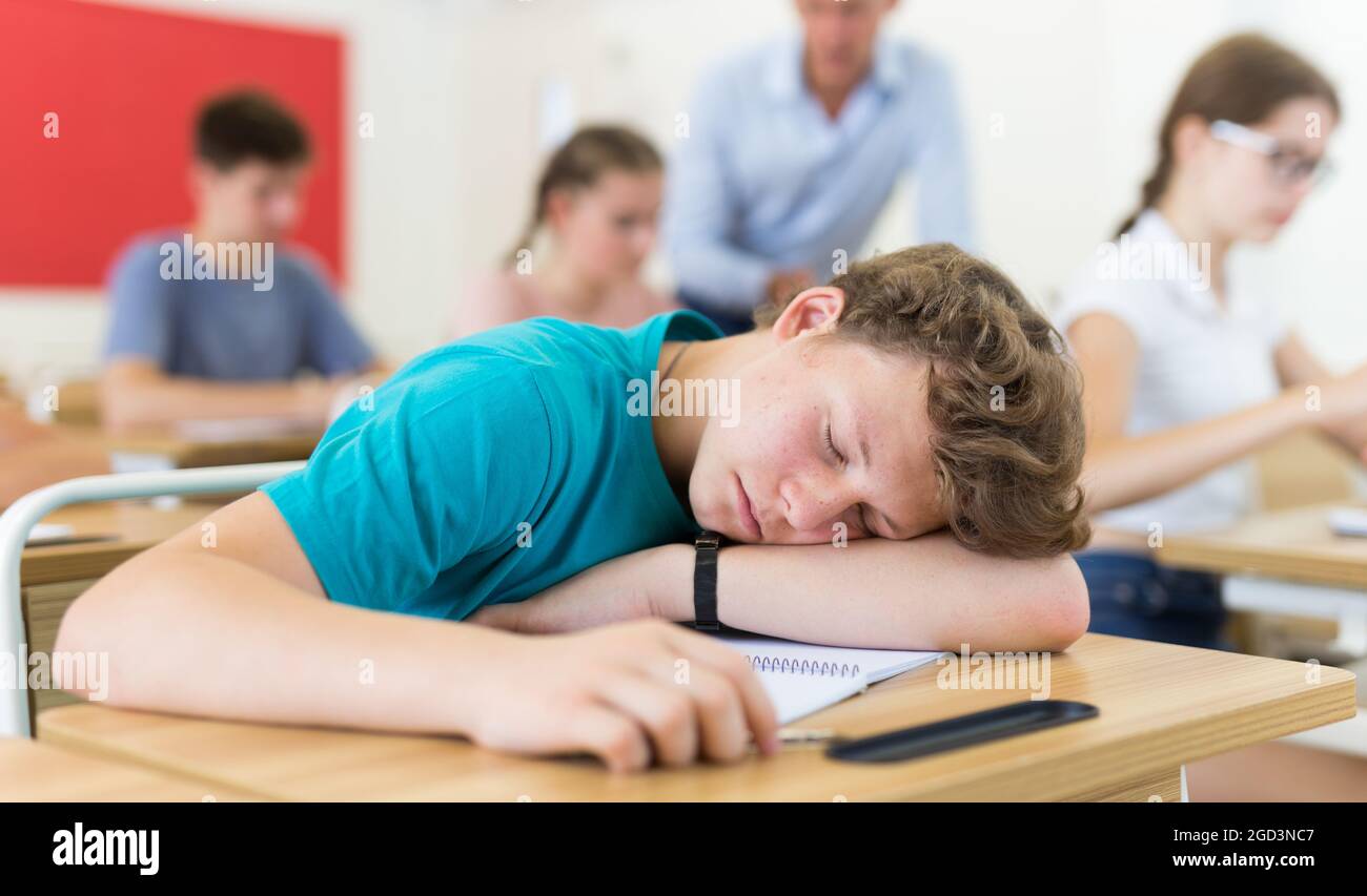 Teenager boy lying on desk Stock Photo