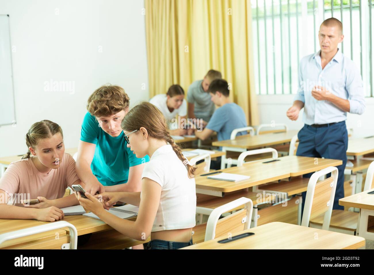 Classmates and teacher working in groups to complete task during class ...