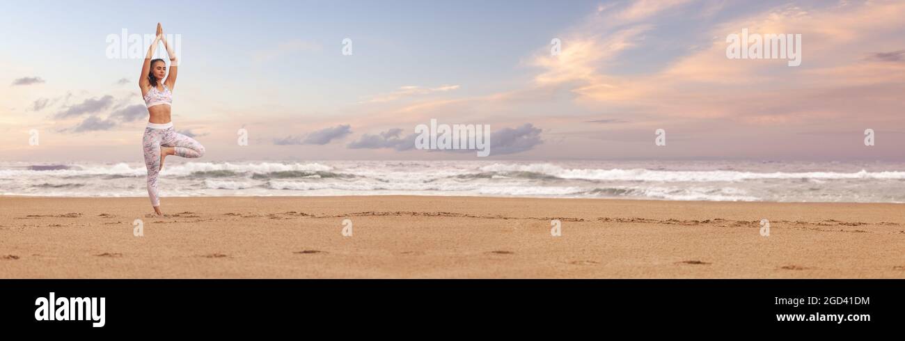 Young woman practicing yoga on the sea beach. Wide panoramic horizontal design with copy space Stock Photo