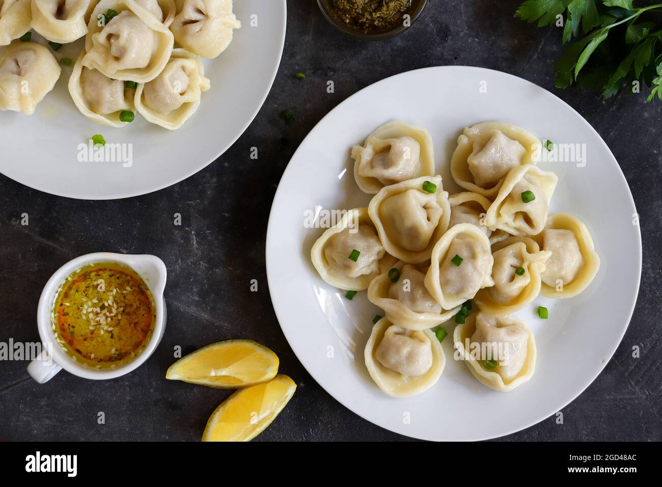 Boiled meat dumplings in a white plate. The concept of a delicious lunch or dinner. Dumplings with green onions. Top view. Stock Photo