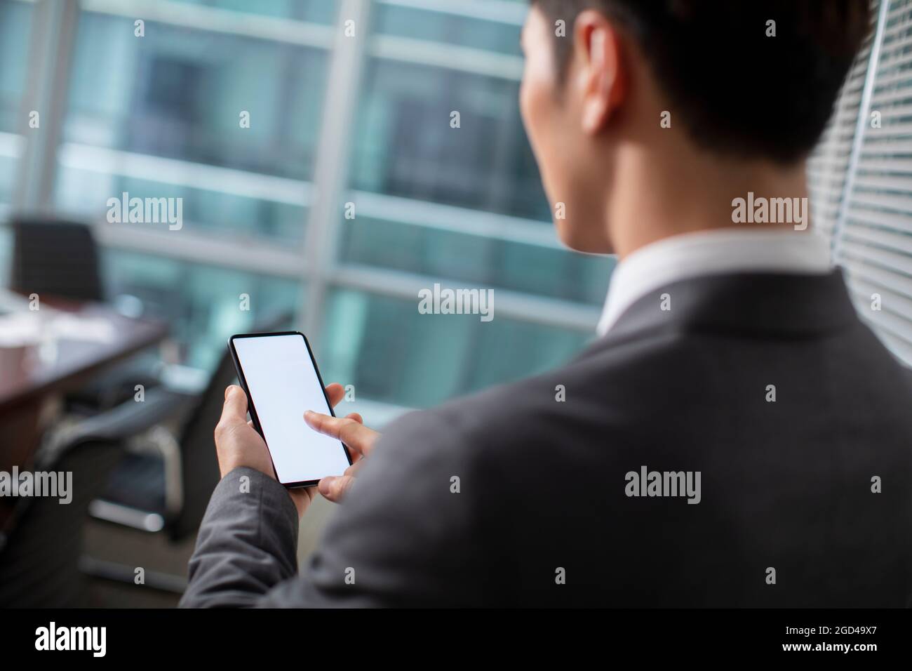 Confident businessman using smartphone in office Stock Photo