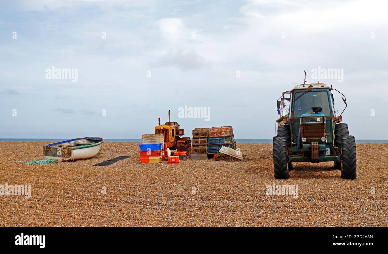 Tractor, boat, and equipment for inshore fishing stored above high water on the shingle beach at Cley-next-the-Sea, Norfolk, England, United Kingdom. Stock Photo