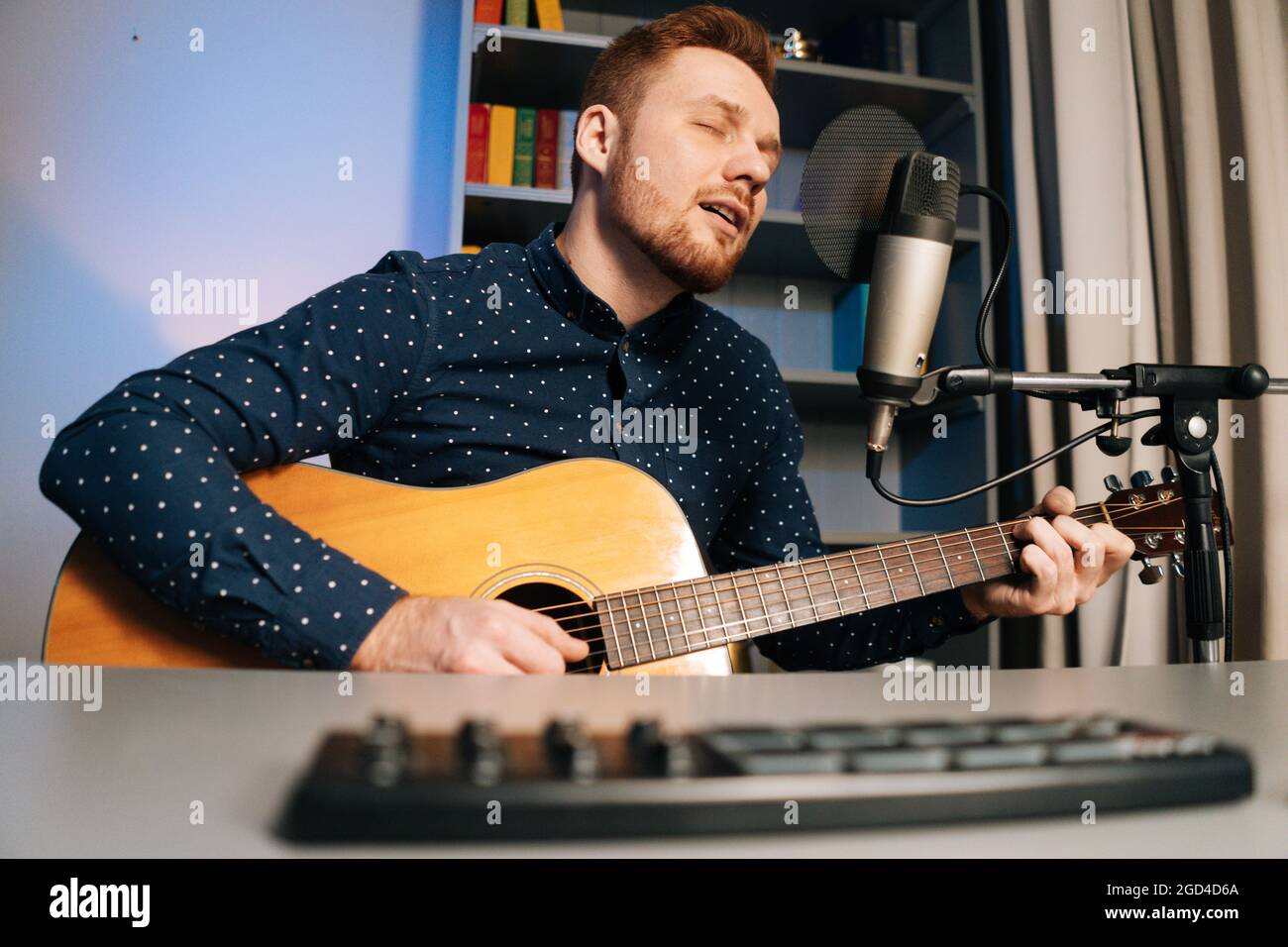 Low-angle view of guitarist singer man play on acoustic guitar recording  sing song using professional microphone stand at home studio Stock Photo -  Alamy