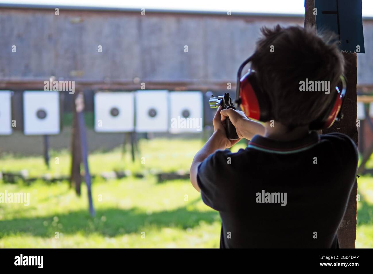 Young boy concentrates while shooting from a revolver at a shooting range Stock Photo