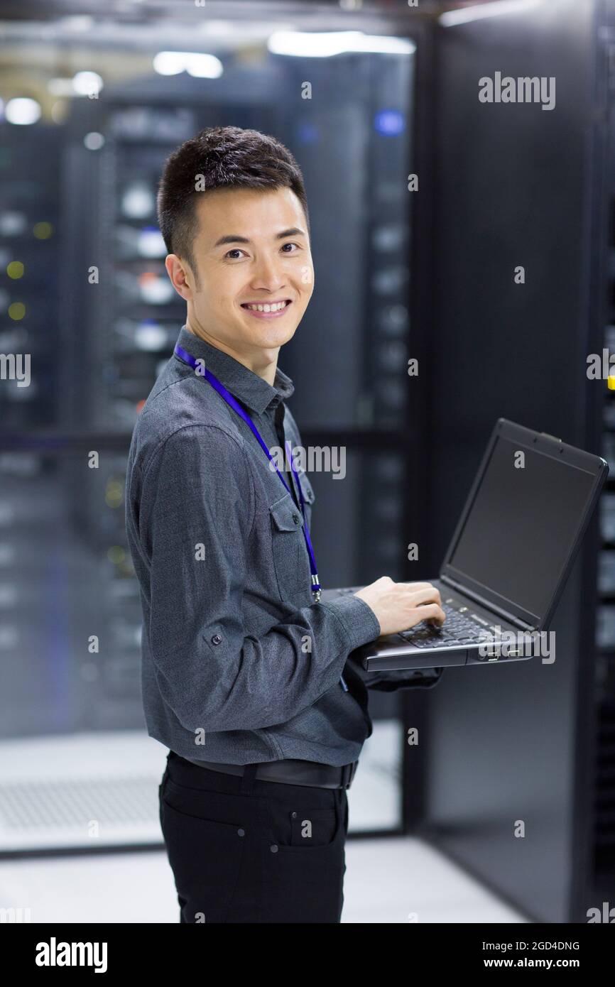 Technician using laptop in computer room Stock Photo