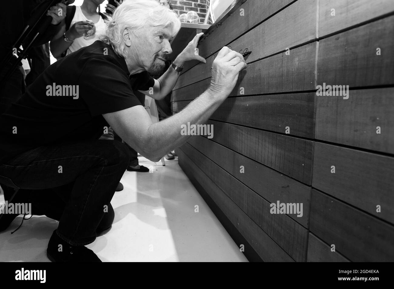 JOHANNESBURG, SOUTH AFRICA - Jan 06, 2021: A grayscale shot of Richard Branson signing autographs at Virgin Mobile for a Guinness World Record attempt Stock Photo
