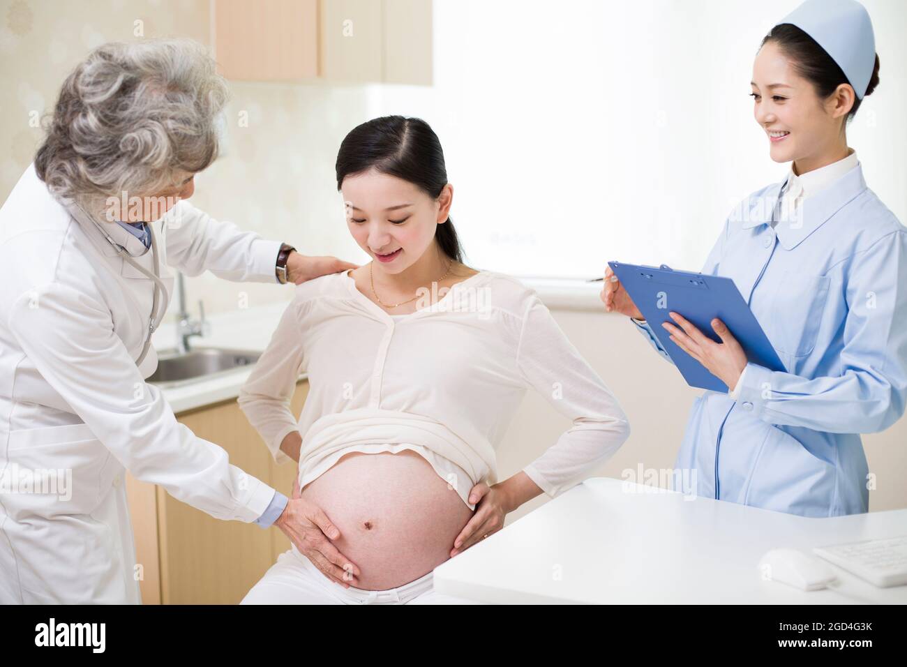 Pregnant woman receiving medical examination from senior doctor Stock ...