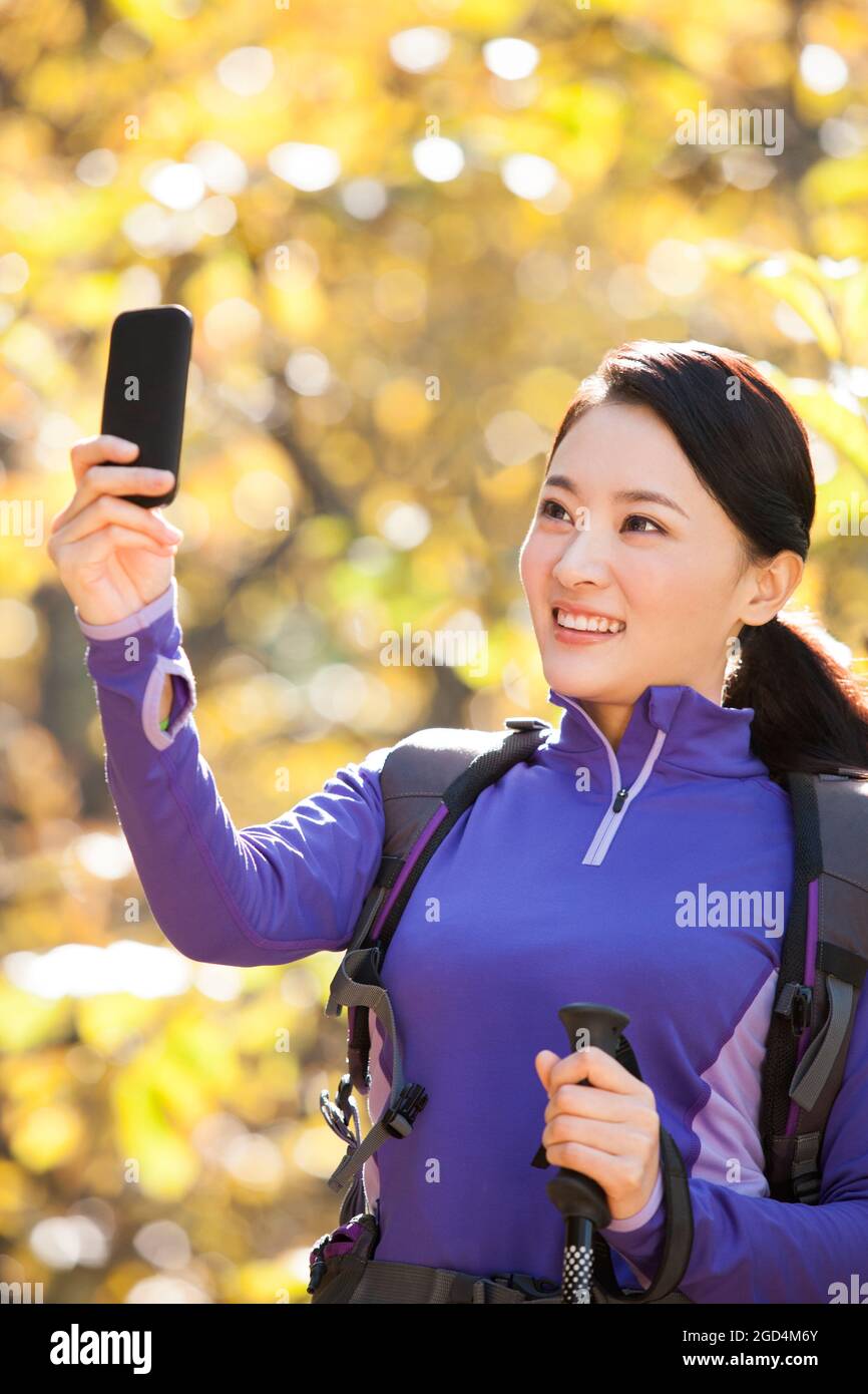 Happy female backpacker taking pictures with smart phone Stock Photo ...