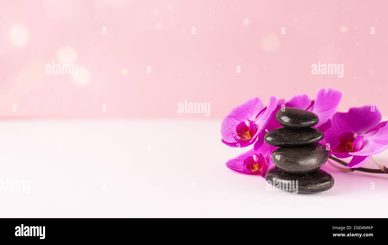 Orchid flower and black pebble spa stones over pink background. Beauty spa  banner Stock Photo - Alamy