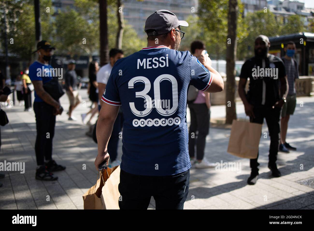 Paris, France. 11th Aug, 2021. A supporter wears a jersey of PSG's Argentinian football player Lionel Messi, that he has just bought at the Paris-Saint-Germain (PSG) football club store on the Champs Elysees avenue in Paris on August 11, 2021. Messi signed on August 10, 2021 a two-year deal with PSG with the option of an additional year. The 34-year-old will wear the number 30 in Paris, the number he had when he began his professional career at Barca. Photo by Raphael Lafargue/ABACAPRESS.COM Credit: Abaca Press/Alamy Live News Stock Photo