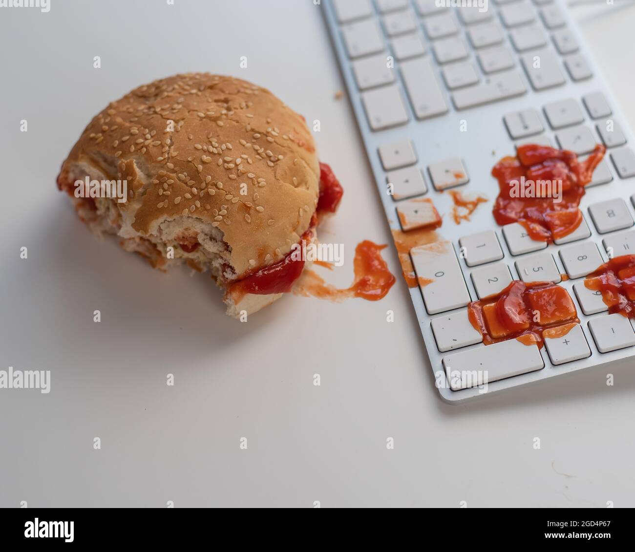 Burger and drops of ketchup on computer keyboard on white desktop Stock ...