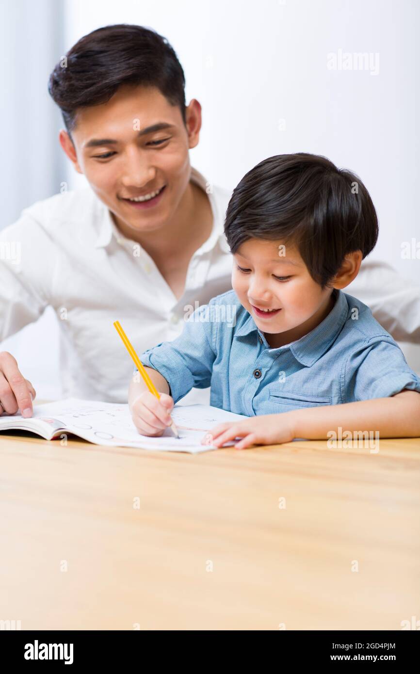 Father helping son with his homework in living room Stock Photo - Alamy