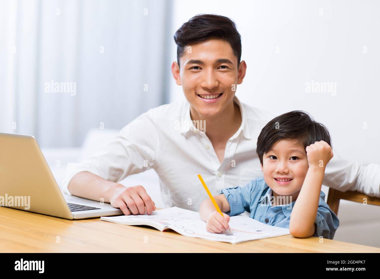 Father helping son with his homework in living room Stock Photo - Alamy