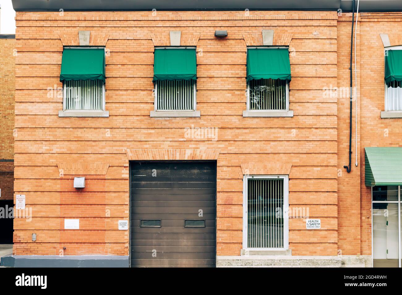 Vintage peach coloured brick building with green awnings and brown garage door in London, Ontario, Canada. Stock Photo
