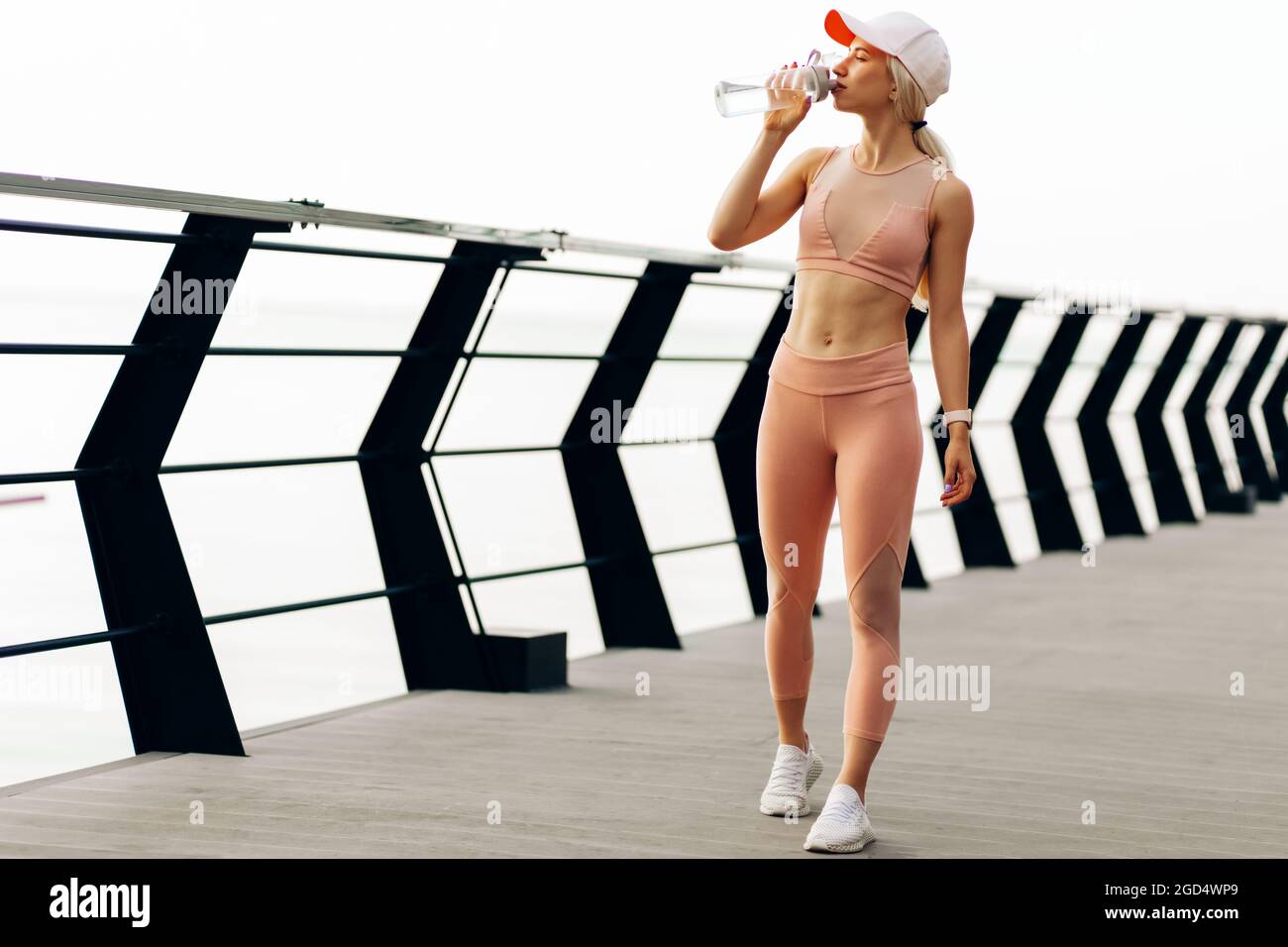 https://c8.alamy.com/comp/2GD4WP9/shot-of-a-beautiful-woman-runner-standing-outdoors-holding-a-bottle-of-water-fitness-woman-taking-a-break-after-running-workout-on-the-bridge-on-the-2GD4WP9.jpg